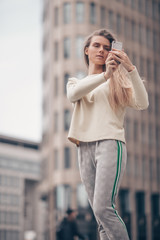 Beautiful woman is making a picture using a mobile phone near modern office building