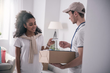 Obraz premium Money transaction. Delighted nice woman smiling while giving the credit card to the courier