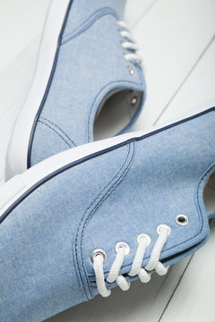 Blue sneakers with white laces on a light background.