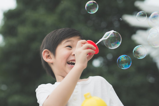 asian child is blowing a soap bubbles