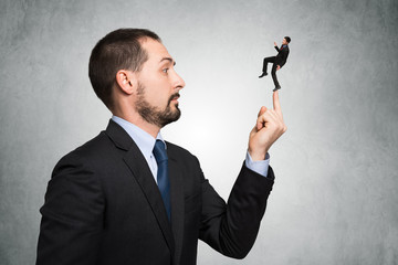 Big businessman keeping a smaller one on his fingertip