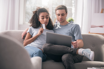 Obraz premium Electronic payment. Positive nice couple looking at the laptop screen while doing an electronic payment