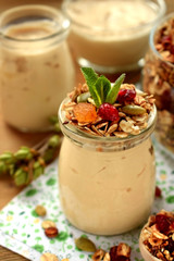 Yogurt in a glass jar topped with granola and mint. Breakfast idea