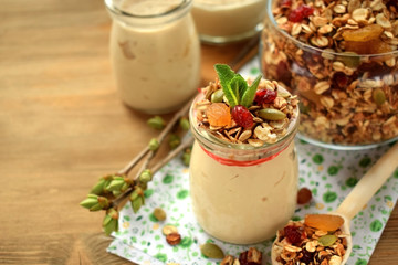 Yogurt in a glass jar topped with granola and mint. Breakfast idea