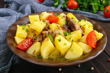 Stewed potatoes with meat in a ceramic bowl on a wooden table.