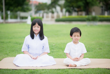 Asian child feeding deer wearing white dress meditating