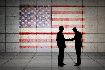 Silhouettes shaking hands against usa flag in grunge effect