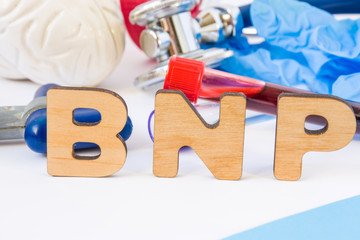 BNP abbreviation or acronym in foreground in laboratory scientific or medical practice meaning brain natriuretic peptide, with model of brain, neurological hammer laboratory test tubes