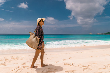 young woman at the beach during vacation at the tropical islands of the Seychelles with huge...
