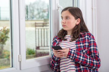 teenager using phone near the window