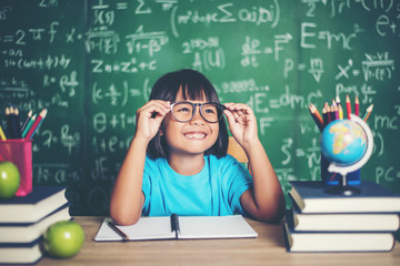 Thoughtful little girl with book near a school board