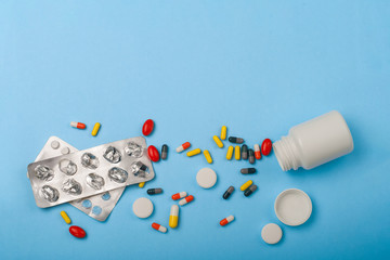 Fototapeta na wymiar Medicine bottle, blister pack and pills closeup on blue background