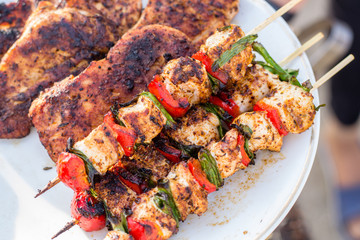 Close up pf delicious chicken breast on wooden skew with fresh vegetables, garlic, paprika fried on mangal barbeque grill
