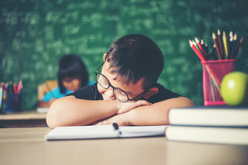 Boy sleeping on the books in the classroom.