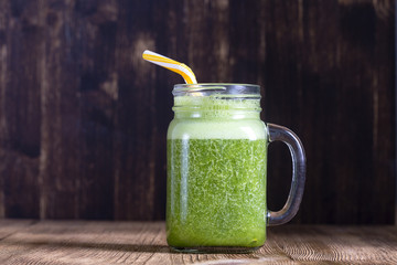 Fresh green smoothie from avocado, banana, parsley and honey on wooden background, close up