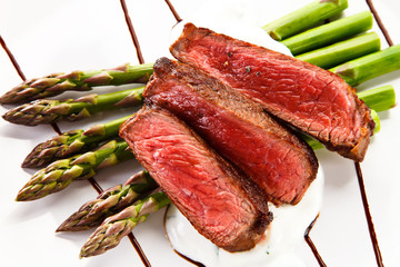 Grilled beef steaks with asparagus on white background