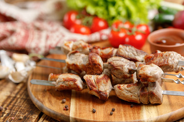 Pork shish kebabs on skewers with fresh vegetables. Appetizing meat cooked on an open fire.