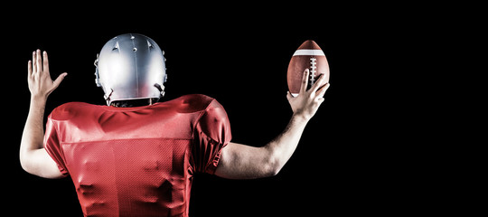 Fototapeta na wymiar Rear view of American football player gesturing while holding ball against black