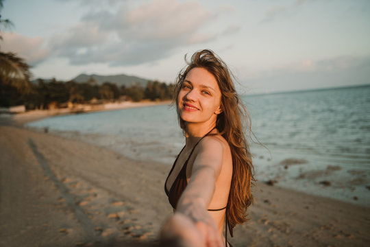 Cheerful woman holding photographer hand on beach