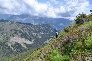 Fototapeta na wymiar Man backpacking down to a mountain landscape Italian Alps