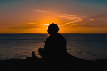 Female silhouette in front of a seaside sunset