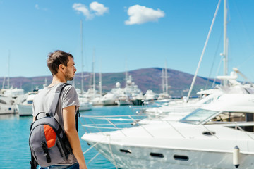 Young tourist looking at beautiful marina with luxurious yachts