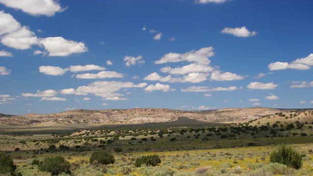 Time-lapse cloud shadows over arid hills and blooming desert valley