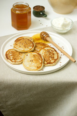 Linen pancakes served with honey and cream cheese on a light background. Rustic style.