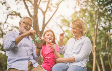 happy family in green nature park on summer ,grandfather blow soap bubbles along with grandchildren