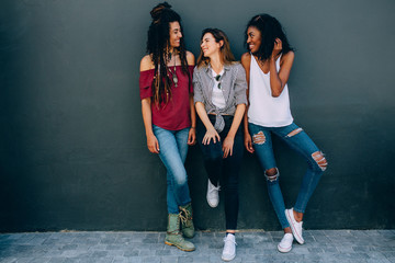 Friends in fashionable clothing standing against a wall