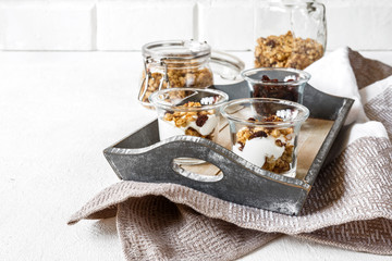Grnola, raisins, milk in glass jars and various ingredients for a super meal with copy space on a light background