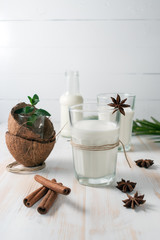 Shell of coconut and coconut milk in glass with cinnamon on wooden table.