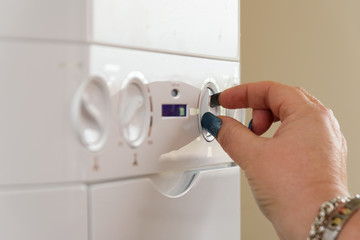 Woman with long nails turning the controls of a British Combi Gas Boiler