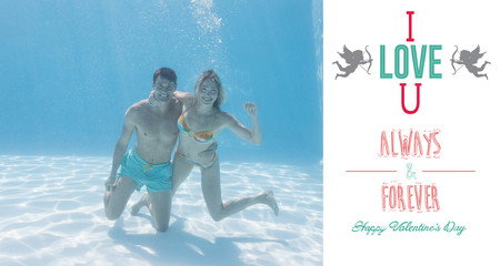 Cute couple smiling at camera underwater in the swimming pool against i love you message