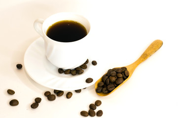 a cup of coffee on a saucer, scattered coffee beans, a wooden spoon, a white background