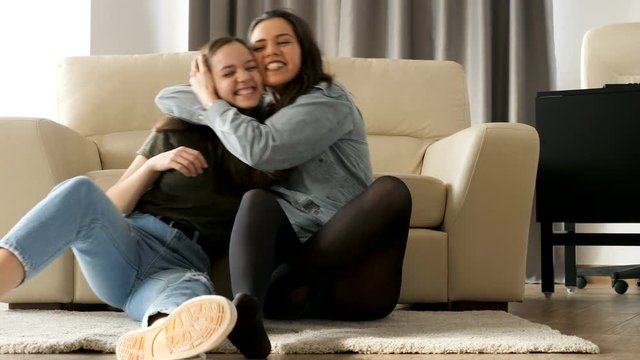 Happy sisters playing with each others on the floor in the living room