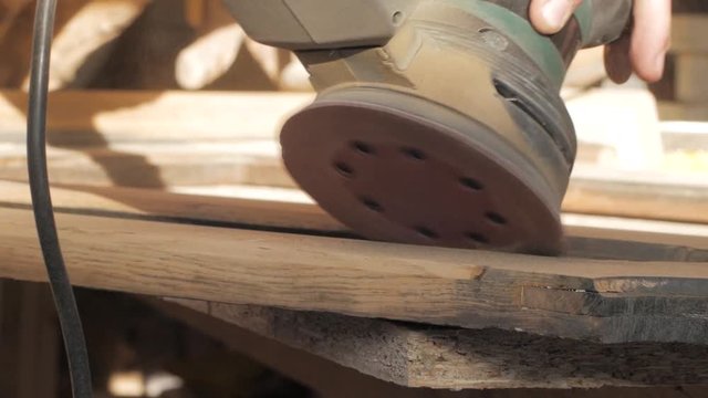 Close up of electric sander working with wood, carpenter in workshop
