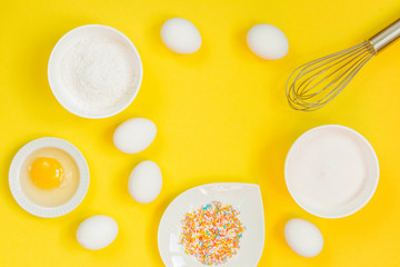 concept of the Easter bakery, various products for home baking, sugar, eggs and flour, coconut munt, top view, empty space for text on a yellow background in the style of pop art mocap layout