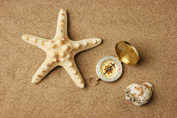 Fototapeta na wymiar compass and starfish on a sandy beach