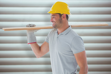 Worker with plank of wood against grey shutters