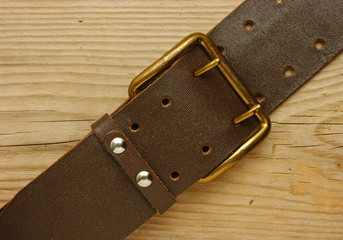 leather belt with a buckle on a wooden board