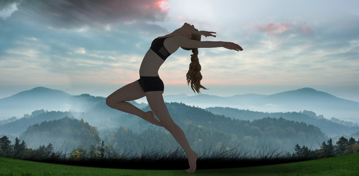 Side view of a sporty young woman stretching against sun shining over mountains