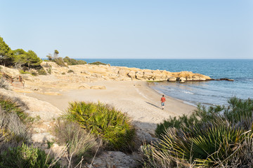 Hombre joven paseando por una idílica y solitaria playa del mediterráneo al atardecer. Costa Azahar. España.