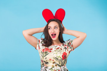Pretty young woman fooling around with red slippers on blue background