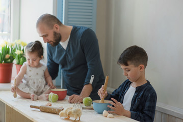 Dad with his little son and daughter baking together.