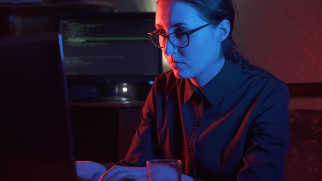 girl hacker in glasses at the computer types concept idea