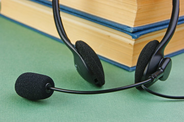 Headphones with a microphone and a stack of books on a green background