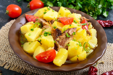 Stewed potatoes with meat in a ceramic bowl on a wooden table.