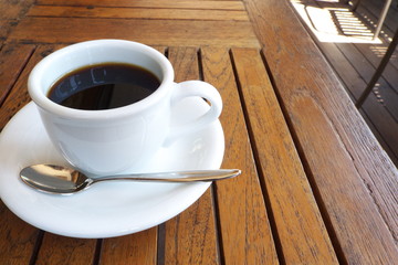 カフェのテラス席のコーヒー - A cup of coffee on the table at the outdoor wooden terrace
