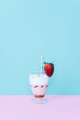 Milkshake with straw and strawberry.